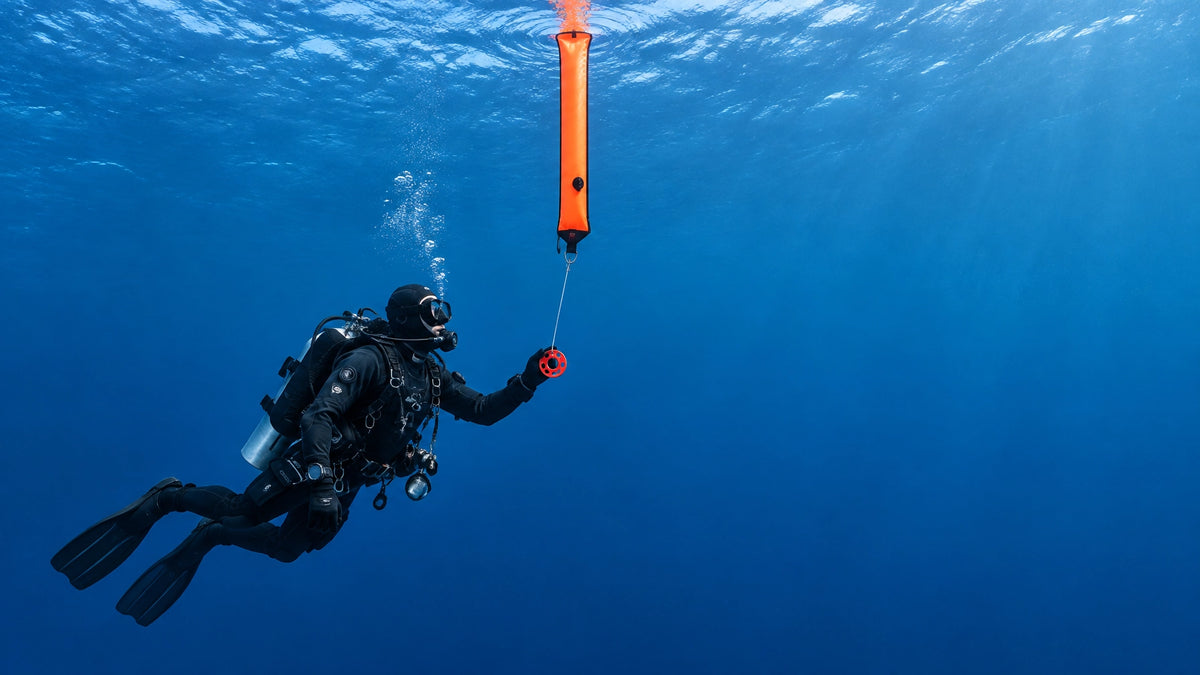Taucher setzt eine orangefarbene Surface Marker Buoy mit Finger-Spool im Freiwasser