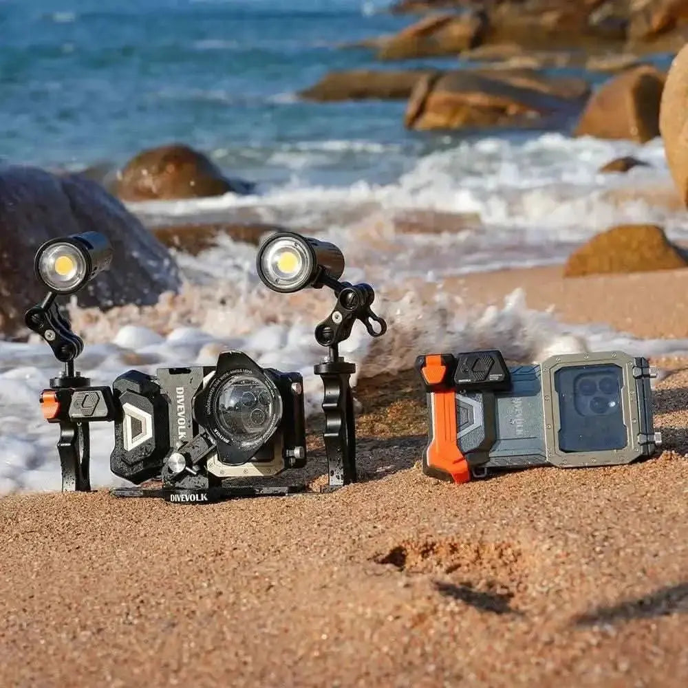 Divevolk external underwater trigger with dual handle and two adapters on sandy beach near ocean.